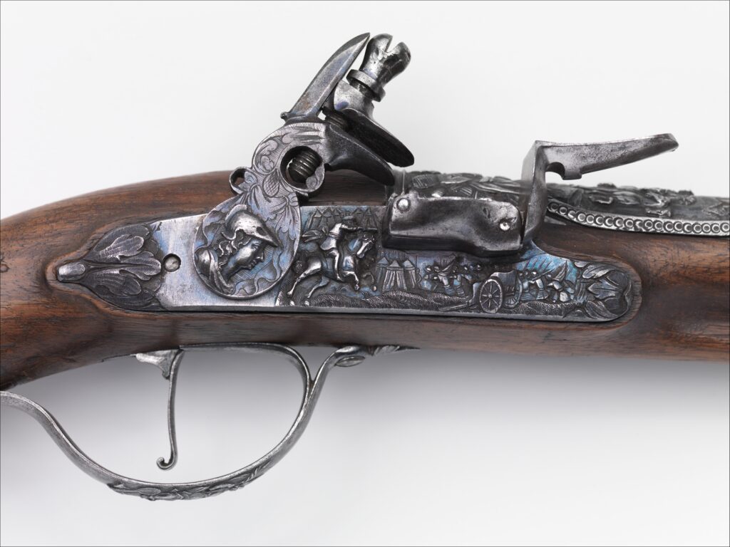 Detail from a Belgian flintlock pistol, showing scenes of early 17th century warfare, demonstrating the craftsmanship of these pieces.